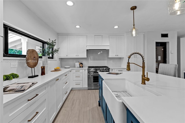 kitchen featuring white cabinetry, sink, pendant lighting, light hardwood / wood-style floors, and high end stainless steel range