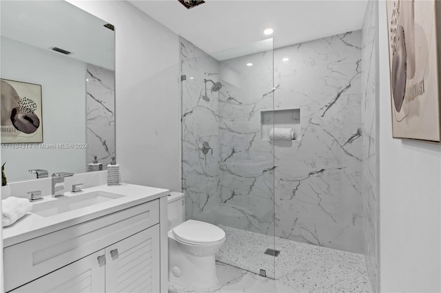 bathroom featuring tiled shower, vanity, and toilet