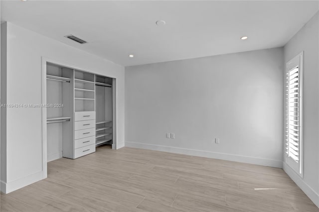 unfurnished bedroom with a closet and light hardwood / wood-style floors