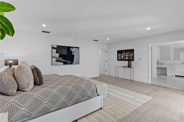 bedroom featuring light wood-type flooring and connected bathroom