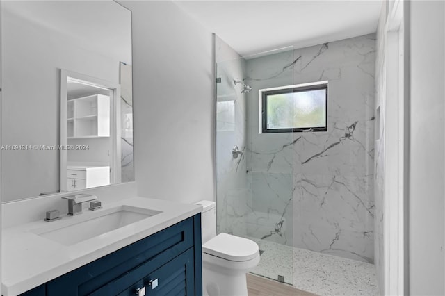 bathroom with tiled shower, vanity, hardwood / wood-style flooring, and toilet