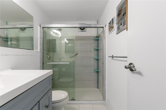 bathroom featuring tile patterned floors, vanity, a shower with shower door, and toilet