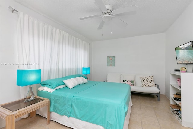 tiled bedroom with ceiling fan and a textured ceiling