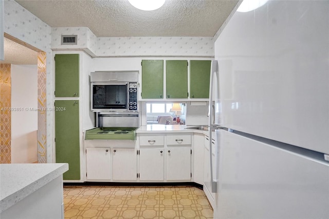 kitchen with white cabinets, a textured ceiling, and white refrigerator