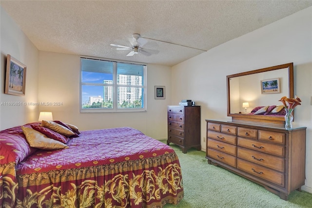 bedroom featuring ceiling fan, light colored carpet, and a textured ceiling