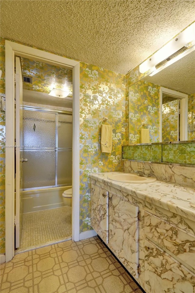 full bathroom featuring sink, toilet, shower / bath combination with glass door, and a textured ceiling