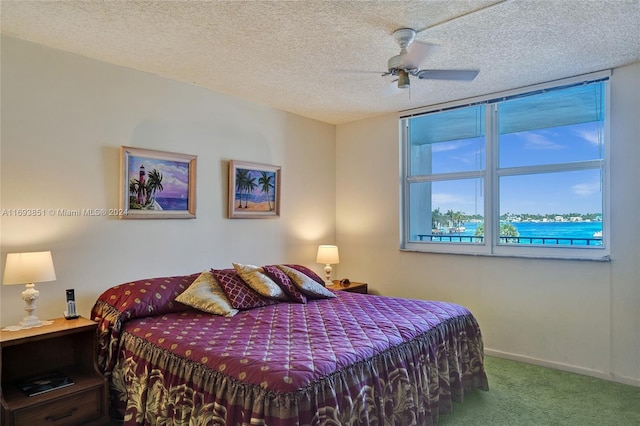 bedroom featuring a textured ceiling, carpet floors, a water view, and ceiling fan