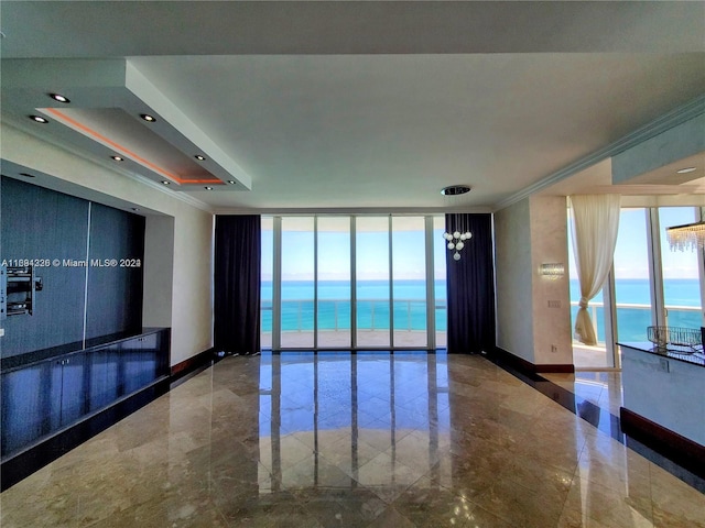 unfurnished room with floor to ceiling windows, crown molding, and a water view