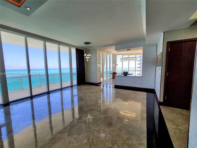 unfurnished room featuring a water view, an inviting chandelier, and a wall of windows