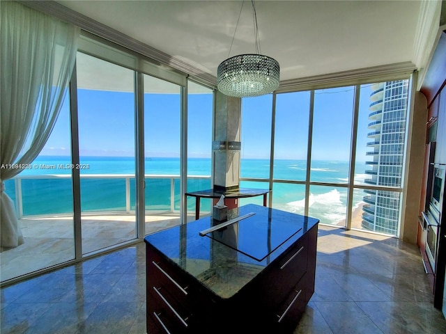 kitchen with an inviting chandelier, a water view, a kitchen island, and dark stone counters