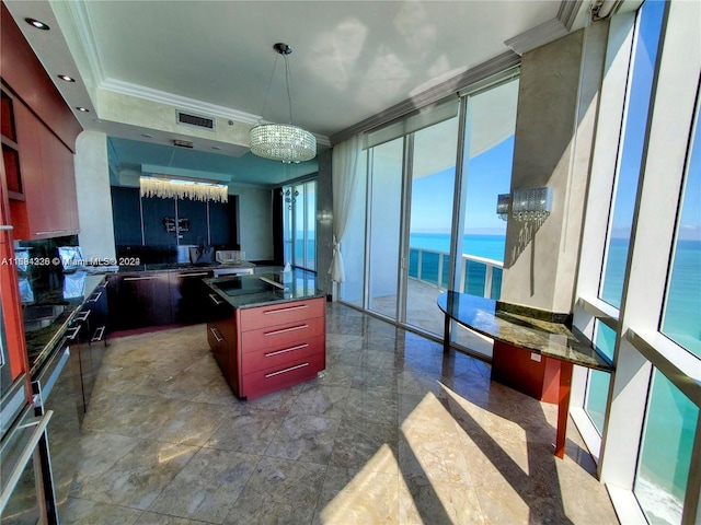 kitchen with a center island, an inviting chandelier, a water view, crown molding, and black stovetop