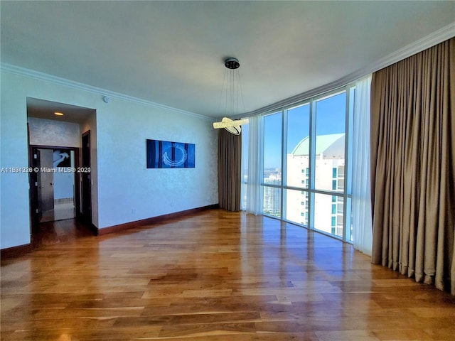 unfurnished room with a chandelier, hardwood / wood-style flooring, and crown molding