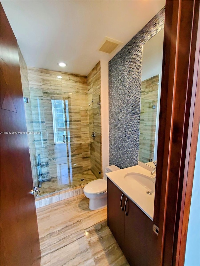 bathroom with tile walls, vanity, an enclosed shower, and toilet