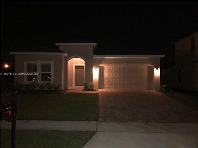 view of front of property with a garage and a lawn