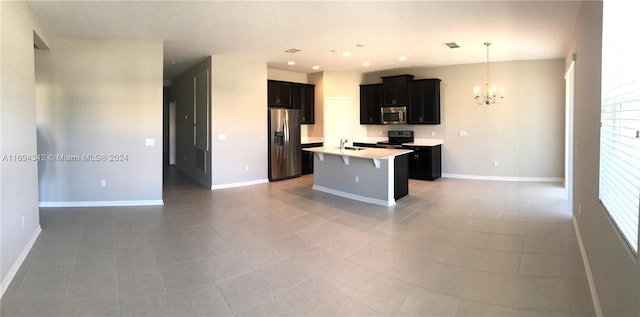 kitchen featuring a kitchen island with sink, hanging light fixtures, sink, stainless steel appliances, and a chandelier