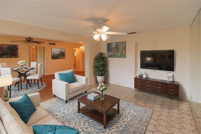 living room with ceiling fan with notable chandelier and a textured ceiling