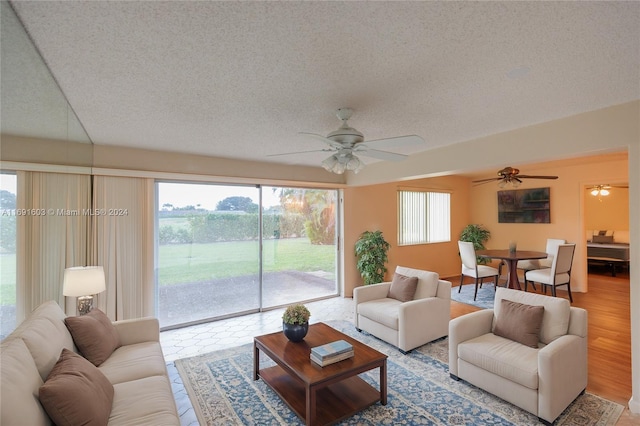 living room featuring ceiling fan, light hardwood / wood-style floors, and a textured ceiling