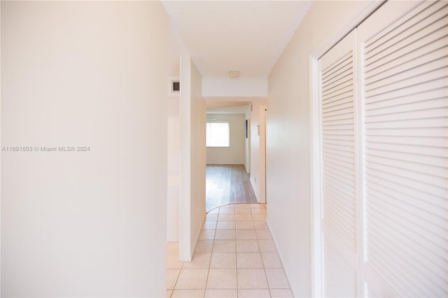 corridor featuring a textured ceiling and light tile patterned flooring