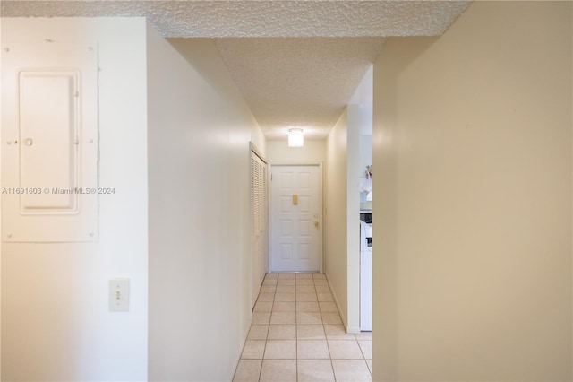 hall with light tile patterned flooring, a textured ceiling, and electric panel