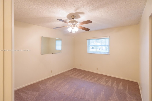 carpeted empty room with ceiling fan and a textured ceiling