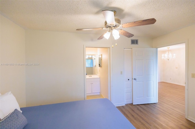 bedroom featuring ensuite bathroom, a textured ceiling, ceiling fan with notable chandelier, light hardwood / wood-style flooring, and a closet