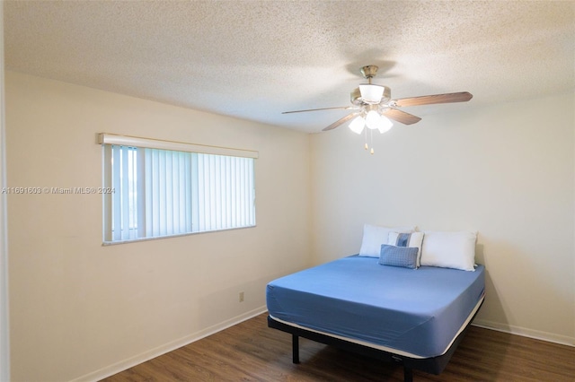 bedroom with a textured ceiling, ceiling fan, and dark wood-type flooring