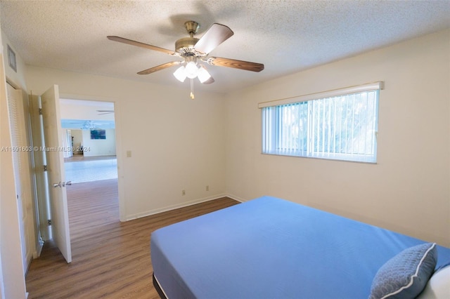 bedroom featuring ceiling fan, wood-type flooring, and a textured ceiling