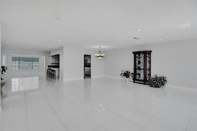 tiled empty room featuring a chandelier