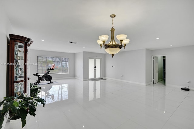 spare room with light tile patterned flooring, an inviting chandelier, and french doors