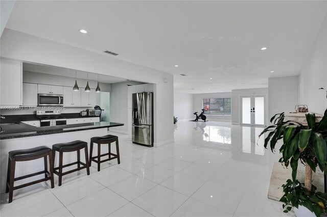 kitchen with decorative light fixtures, white cabinetry, a kitchen bar, kitchen peninsula, and stainless steel appliances