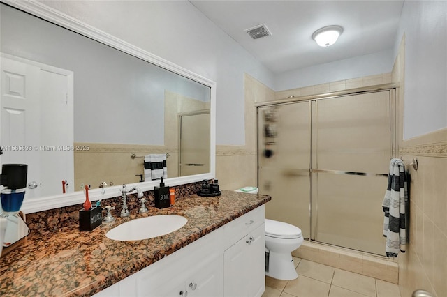 bathroom with tile walls, vanity, a shower with shower door, tile patterned floors, and toilet