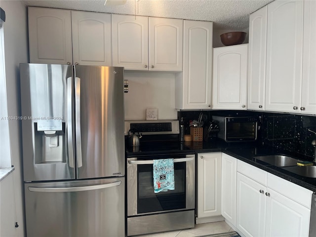 kitchen featuring decorative backsplash, white cabinetry, light tile patterned floors, and stainless steel appliances