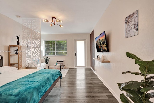 bedroom with an AC wall unit, dark hardwood / wood-style flooring, and an inviting chandelier