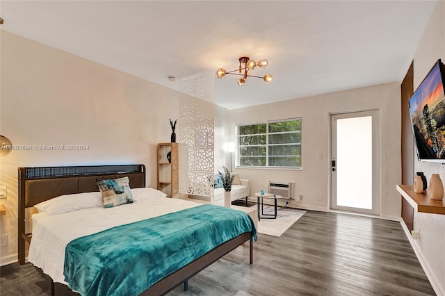 bedroom featuring an AC wall unit, a notable chandelier, and hardwood / wood-style flooring