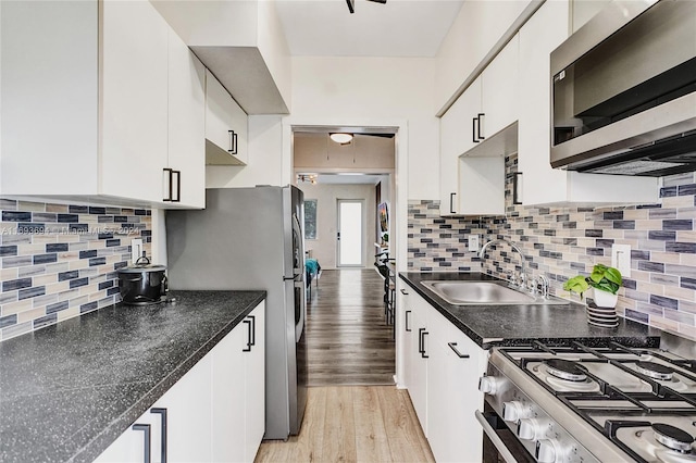 kitchen featuring sink, light hardwood / wood-style flooring, appliances with stainless steel finishes, tasteful backsplash, and white cabinetry