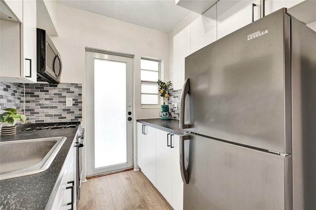 kitchen featuring stainless steel appliances, white cabinetry, tasteful backsplash, and light hardwood / wood-style flooring