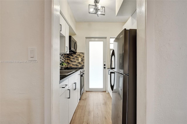 kitchen featuring stainless steel appliances, an inviting chandelier, tasteful backsplash, light hardwood / wood-style floors, and white cabinets