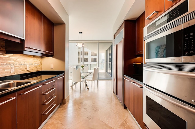 kitchen featuring sink, dark stone countertops, tasteful backsplash, decorative light fixtures, and stainless steel appliances