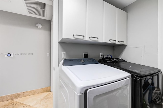 laundry room featuring washer and dryer and cabinets