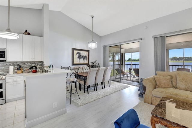 kitchen featuring a water view, decorative backsplash, white cabinets, and pendant lighting