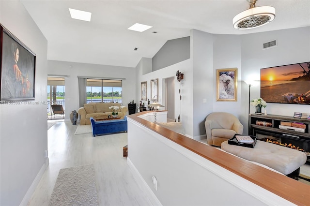 living room with high vaulted ceiling and light wood-type flooring