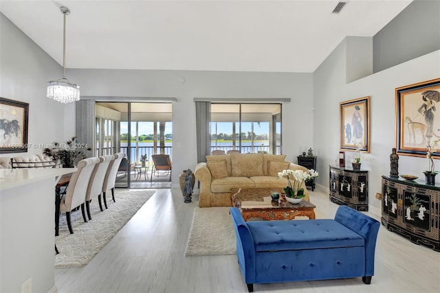 living room featuring light hardwood / wood-style floors, a water view, lofted ceiling, and a chandelier