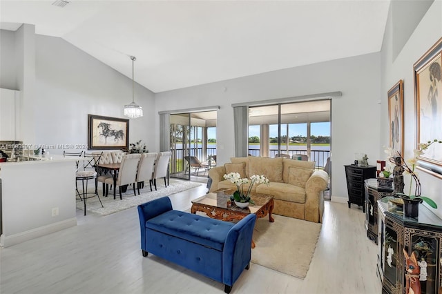 living room featuring a water view, high vaulted ceiling, and light hardwood / wood-style flooring