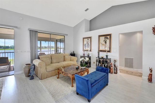 living room featuring high vaulted ceiling, light wood-type flooring, and a wealth of natural light