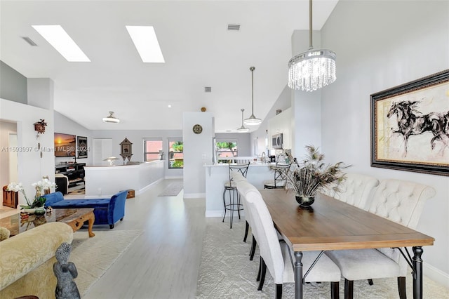 dining space with high vaulted ceiling, a chandelier, and light wood-type flooring