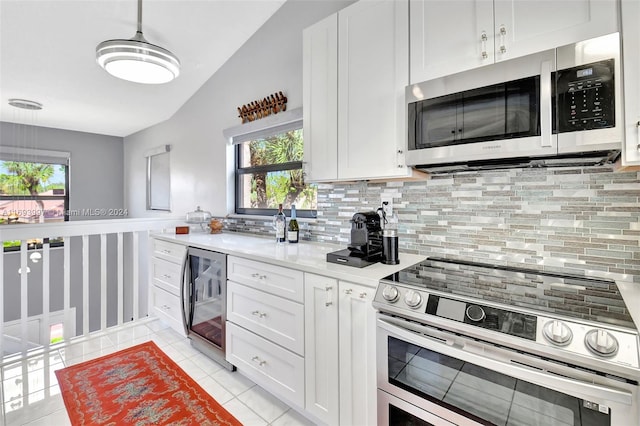 kitchen featuring a wealth of natural light, white cabinetry, beverage cooler, and appliances with stainless steel finishes