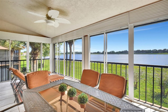 sunroom / solarium with ceiling fan, a water view, a wealth of natural light, and vaulted ceiling