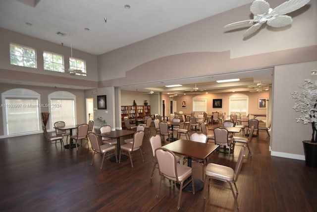 dining space featuring ceiling fan, dark wood-type flooring, and a high ceiling