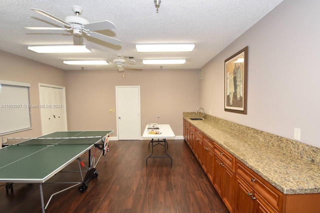 rec room with a textured ceiling, dark hardwood / wood-style floors, ceiling fan, and sink