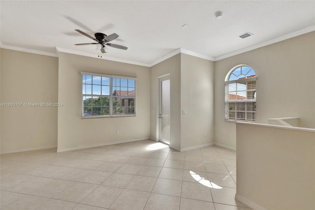 empty room featuring ceiling fan, a healthy amount of sunlight, light tile patterned flooring, and crown molding